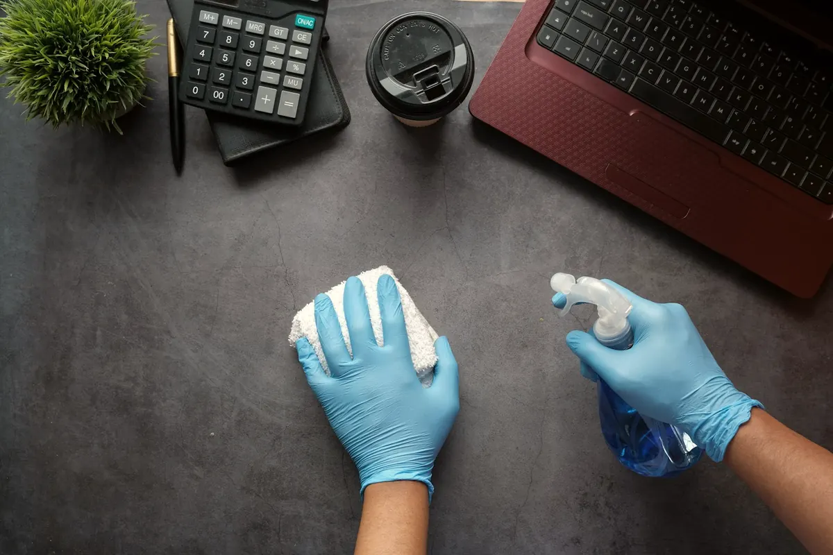 Nettoyage d'un bureau avec gants et vaporisateur