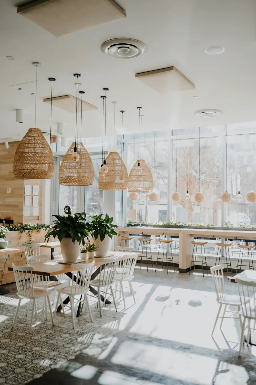 Salle de restaurant claire avec suspensions en rotin